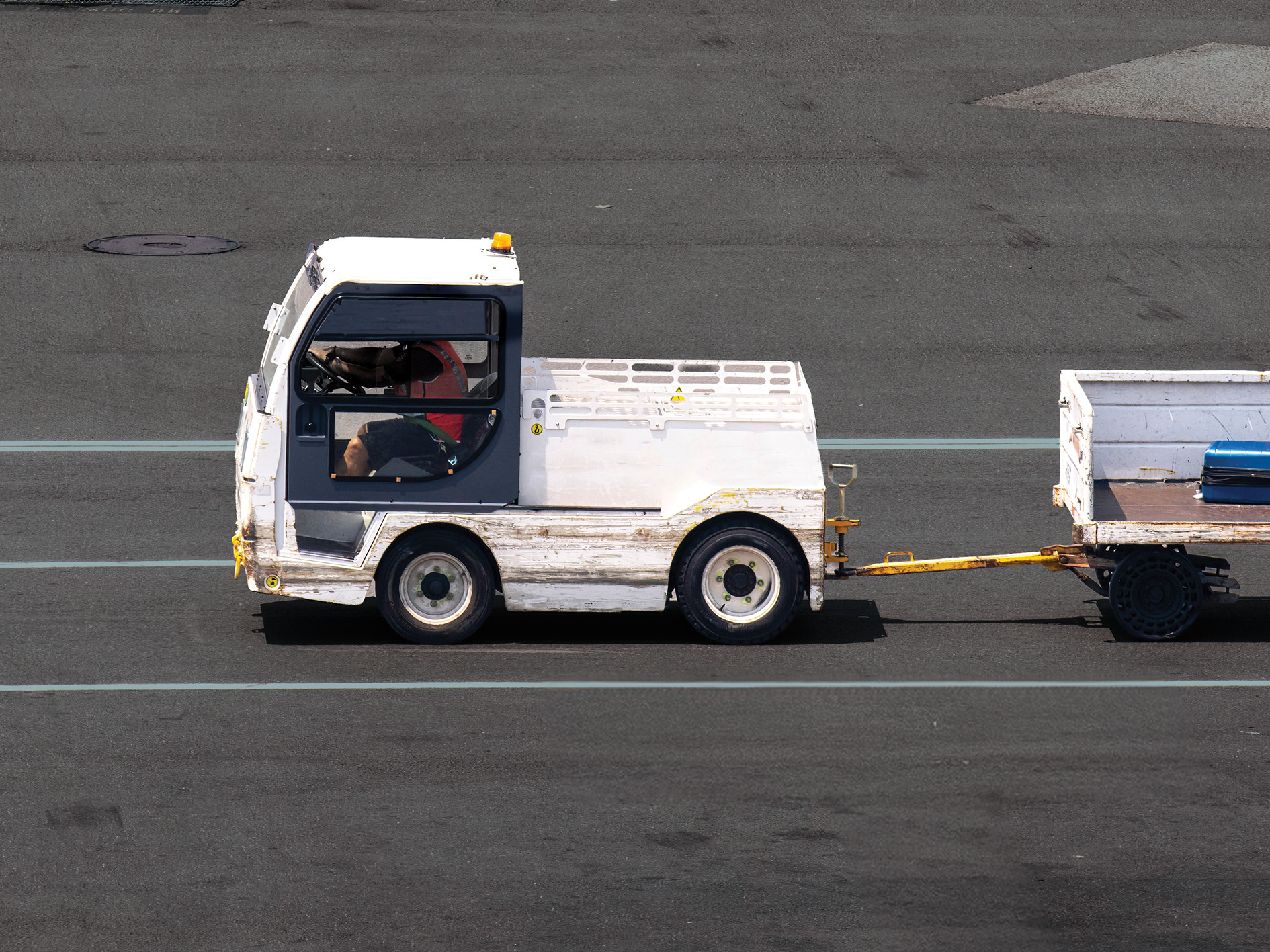White towing truck pulling trailer with a blue suitcase