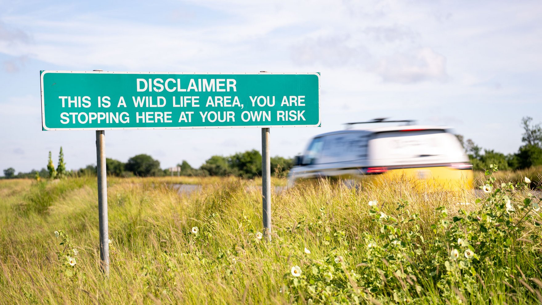 a green road sign is noting that a wildlife area begins here