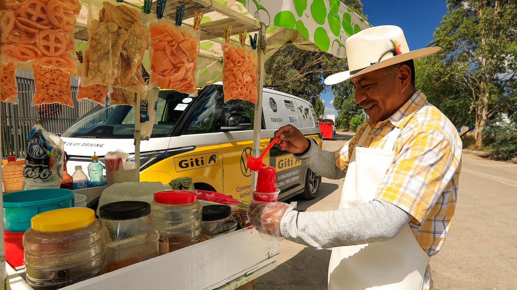 man wearing a white apron and a white hat standing at street vendor cart, serving colorful icecream